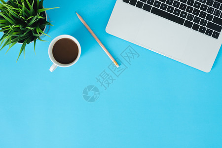 办公桌工作空间平面复制一个工作空间的包括膝上型电脑咖啡杯和小草地放置在蓝色糊面背景上部蓝色背景空间概念图片