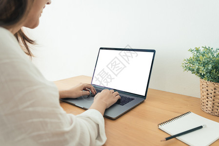在家工作时使用笔记本电脑并空白屏幕打字在家通过便携式计算机工作的商业妇女在家享受时间图片