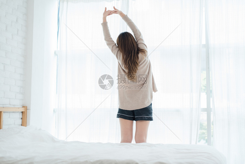 清晨女人做在床上伸展图片