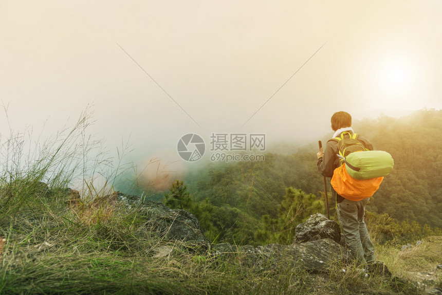 带着背包旅行者在山顶上漫步早在日出时雾感觉自由与美丽的然旅行与假期概念图片