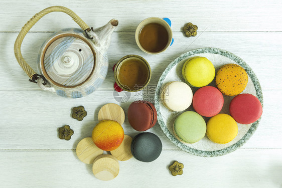 盘子和配茶壶的木制桌子上混合了多彩的法国马卡龙图片
