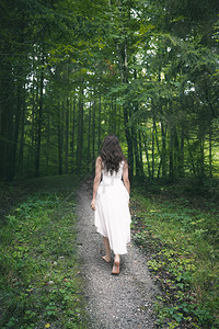 身着优雅的白色裙子赤脚走在一条穿过春林的路上赤脚走着图片