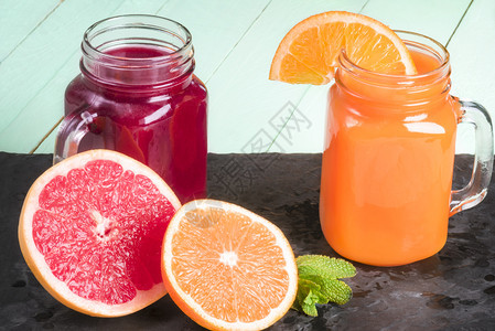 新鲜的橙汁和葡萄花蜜用泥瓦罐在黑石高原上切橙子葡萄汁和薄荷叶接近图片