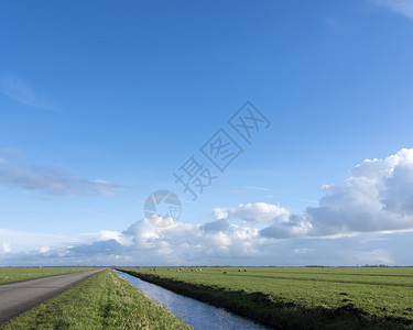 在云层下群居落中巨大的片草地在丘下的乡间和河道之的公路和河道背景图片