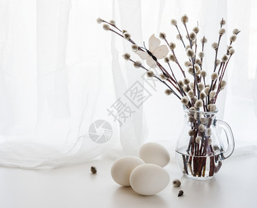 一个透明的玻璃杯和三个白色的东方鸡蛋与白色的透明布图片