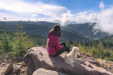 女人和狗欣赏德国的山丘和云层图片