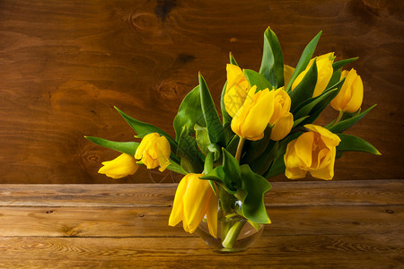 木制背景上的春天黄色郁金香花束春天黄色的郁金香花束在木质背景上复制空间花的问候花的明信片春天的花朵图片