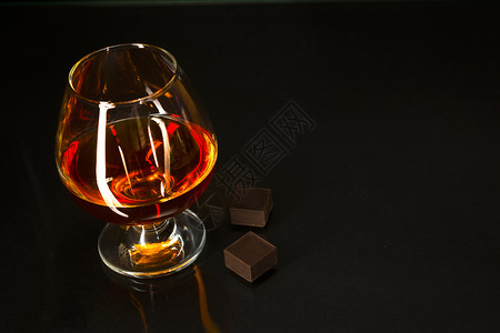 黑底的白兰地玻璃和巧克力白兰地玻璃威士忌白兰地法郎玻璃和黑底的巧克力图片