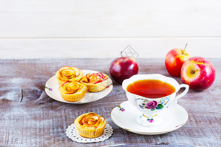 茶杯和苹果玫瑰松饼在生锈的木桌上松饼甜苹果点馅饼高清图片