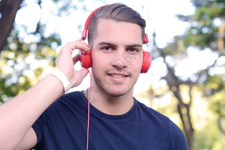 年轻人在公园里拿着耳机户外在公园里拿着耳机的年轻人图片