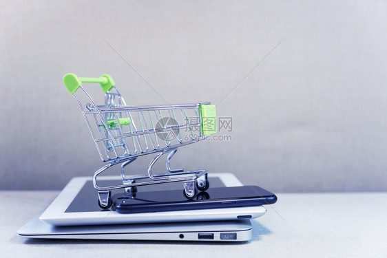 在线商业和电子务或网上购物概念商店在笔记本电脑平板和移动话的堆叠上购物篮子免费复印空间的商业无线技术图片