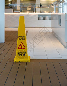 英语和德的湿地板黄色警告锥体现代厨房或德国餐馆的湿地板警告三角体英语和德的湿地板黄色警告锥体图片