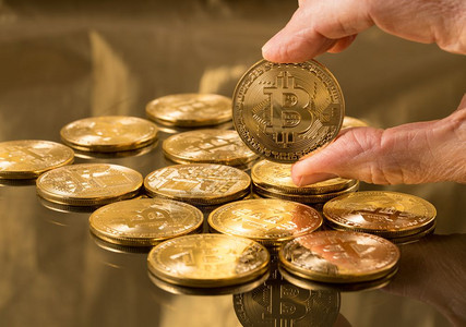 具有金背景的比特币堆叠金背景的比特币堆叠或放在金背景的比特币或堆叠中手握着一枚硬币用于说明块链和网络货币图片