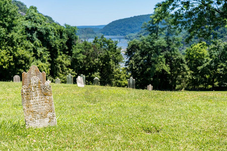 在西弗吉尼亚州竖琴渡轮上方的墓碑旧苔榈和地衣覆盖了墓碑上方的旧苔榈覆盖了竖琴渡轮上的墓碑图片