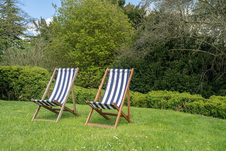 在花园草坪上两张典型的英语甲板椅夏季在英语花园中两张带有脱衣布的英国双张式甲板椅在花园草坪上两张典型的英语甲板椅图片