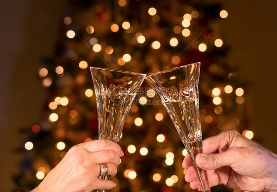 causin老年已婚夫妇的clinkry香槟杯对抗非焦点的xmas树灯香槟用两种水晶笛子对抗圣诞树灯图片
