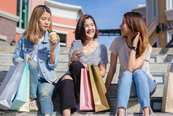 在城市购物时使用智能手机的美丽亚洲女图片