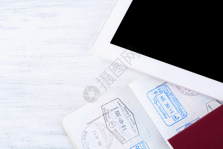 贴有签证印章和平板电脑旅行概念的开放护照图片