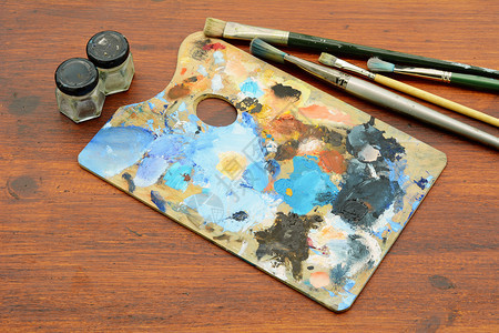 艺术家配有彩色油画笔和木背景上的油漆刷子调色板艺术概念配有彩色油画笔和漆刷子的调色板背景图片