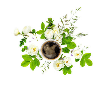 古代装饰成分包括白色瓷杯中的黑咖啡和白色野玫瑰花背景上隔开绿叶图片
