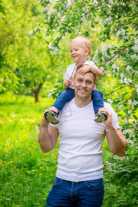 一个快乐的父亲垂直肖像和一个年轻儿子在公园里散步的图片