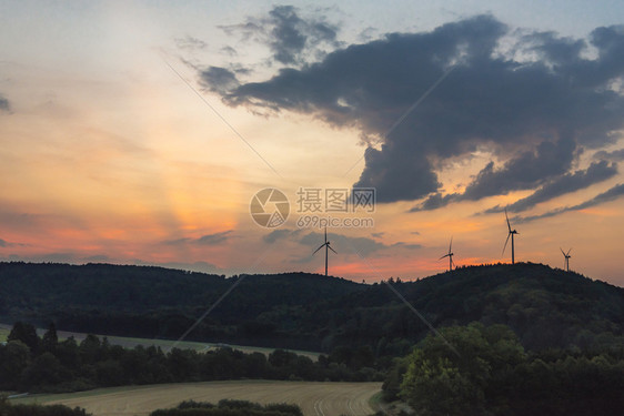 美丽的日出风景地平线上有林山草地和现代风力涡轮机在多彩的天空下靠近德国的盖尔多夫镇图片