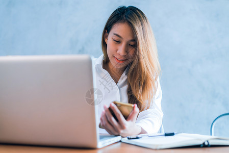 年轻女在桌子上用笔记本电脑工作带着微笑年轻女周末用笔记本电脑工作图片