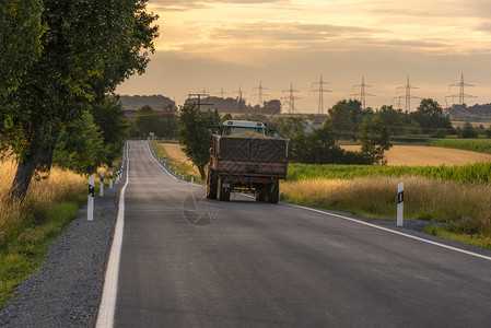 日落时在德国的schwabisal镇附近一辆装满谷物的卡车在长乡村公路上行驶图片