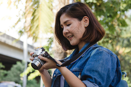 年轻快乐的亚洲女在城市巡演期间用相机拍照欢乐的情绪极好城市概念中的户外生活方式图片