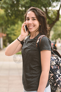 年轻拉丁女人在户外用手机聊天的肖像图片