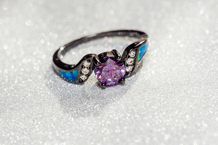 戒指特写黑色时装金戒指紫的铁环在闪发光的背景上背景