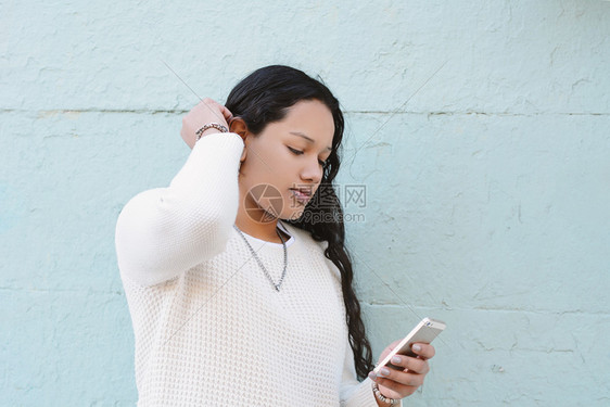 美丽的latin年轻女在街上用智能手机发信息图片