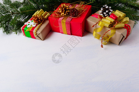 圣诞节背景有鲜树枝和三个礼物盒圣诞节礼物有金珠松果和雪花复制空间图片
