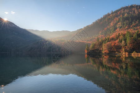 太阳照耀在山上有丰富多彩的秋天森林并反射在阿尔普西湖里在大惊小怪巴伐利亚德意志图片