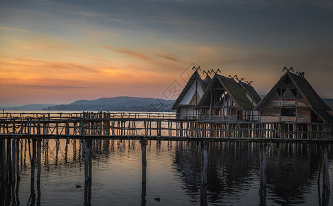 天气恶劣的木屋建筑在柱上造福森湖水上日落多彩图片