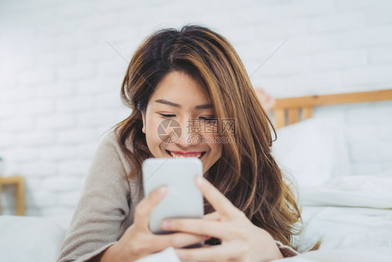 趴在床上玩手机的女孩图片