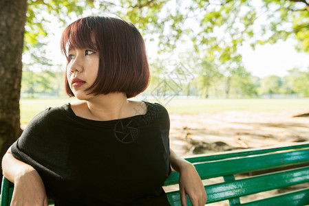 女孩坐在公园的长凳上休息图片