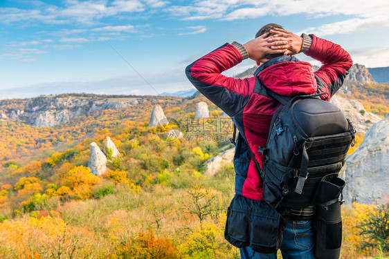 摄影师旅行者背包欣赏秋天美丽的山峰后视图片