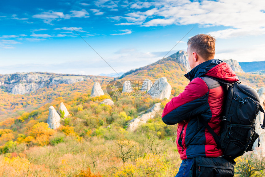 摄影师旅行者带着一个背包欣赏秋天美丽的山峰图片