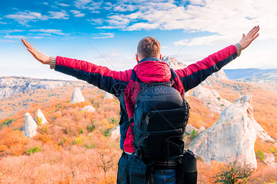 带着一个背包手敞开享受山上秋天风景的游客图片