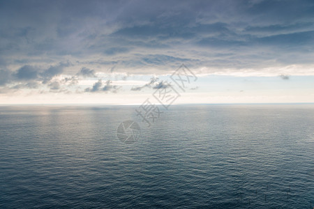 海面表有轻微的波纹可以看到地平线和浓厚的黑雨云雾着美丽的风景背景图片