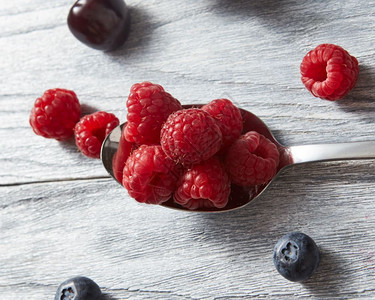 甜的果子放在灰色背景的汤匙上平坦素食理念大勺子红新鲜的草莓灰色背景的背景图片