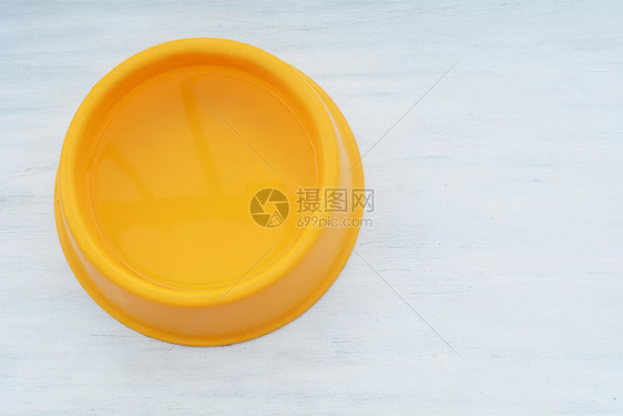 满水的黄色塑料碗白木本底水宠物喂养和照料概念图片