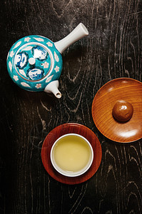 绿色日本茶杯子和手工制陶瓷锅黑色旧木制桌图片