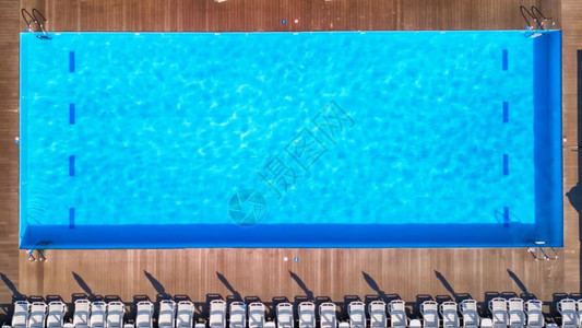 在私人游泳池附近的木制地板上看到防晒霜蓝色游泳池有清洁水蓝色游泳池暑假有白色的太阳床顶层风景图片