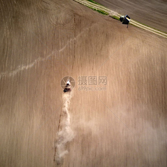 拖拉机播春田后面的一整片粉尘空中观察拖拉机无人驾驶飞拍摄的照片在农业工作春季开始时带种栽培机的空中观察拖拉机图片