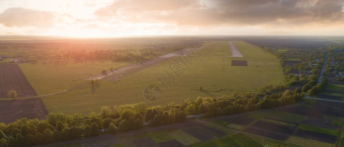 无人驾驶飞机空中摄影风景绿森林农田和破坏小机场以绿色和黑的颜在日落时云天空背景上破坏简易机场无人驾驶飞机鸟类和的空中观察图片