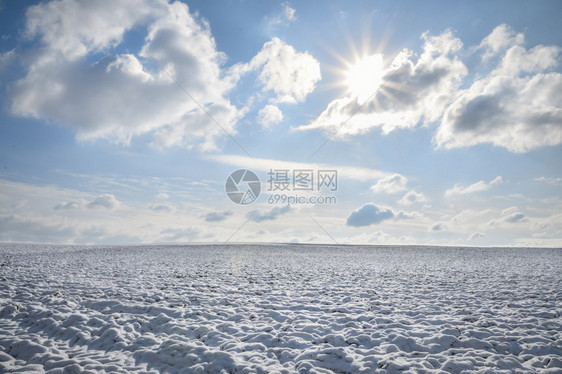 冬季风景一片空旷的草原覆盖在雪中地平线上与蓝天和白云相连阳光下德国图片