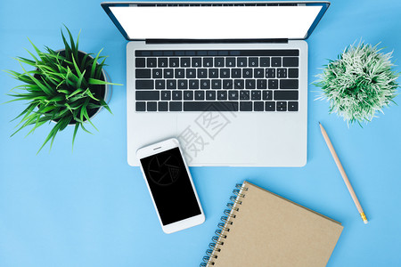 手机海报办公桌工作空间平面用笔记本电脑智能手机和笔记本拍摄工作空间放在蓝色糊面背景上背景