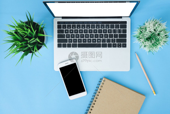 办公桌工作空间平面用笔记本电脑智能手机和笔记本拍摄工作空间放在蓝色糊面背景上图片